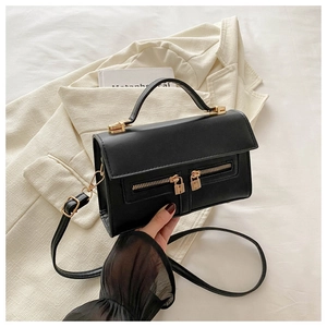 Détail du sac à main en cuir noir avec deux fermetures éclair dorées et bandoulière