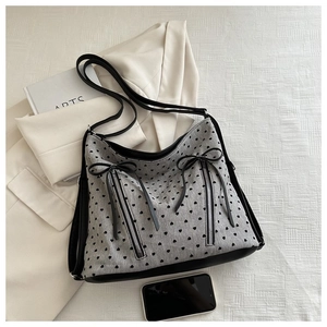 Detail view of large grey heart-print tote bag with twin zippers and bow accents