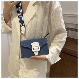 Details einer blauen Denim-Umhängetasche mit weißer Schnalle und breitem Modegurt