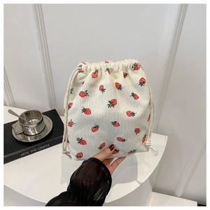 Détail du sac seau en velours côtelé crème avec motifs de fraises rouges texturés