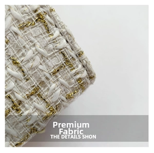 Macro shot of premium white tweed fabric with gold metallic thread and woven textures