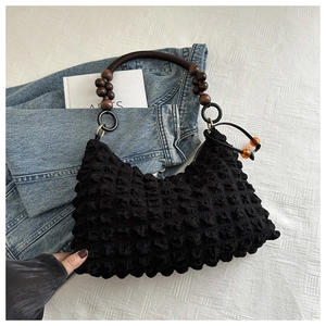 Détail du sac à main noir à texture popcorn avec poignée en perles de bois