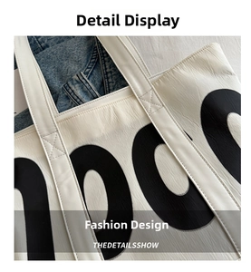 Detail shot of white canvas tote bag with bold black letters and reinforced stitching