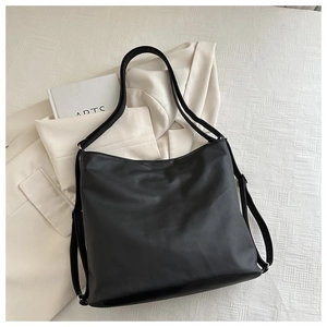 Detail view of large black tote bag with reinforced double straps on beige blazer