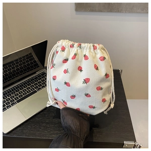 Gros plan du sac seau en velours côtelé blanc avec imprimés fraises rouges et vertes