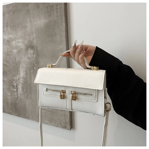 Détail du sac bandoulière en cuir blanc avec double zip et fermoirs dorés chic