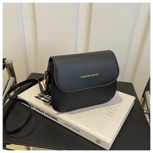 Detail of black matte saddle bag with gold logo and delicate leather grain texture