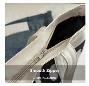 Macro shot of smooth silver metal zipper on a white PU leather tote bag details