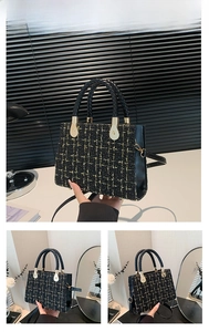 Detail view of woven black and gold tweed handbag with braided handles and golden hardware