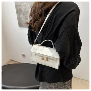 Détail d'un sac bandoulière blanc brillant avec fermetures éclair dorées et poignée