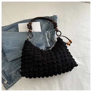 Détail du sac plissé noir avec poignée en perles de bois et breloques couleur ambre