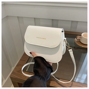 Close-up of white PU leather saddle bag with gold hardware and FASHION & BAGS lettering