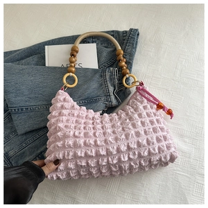 Détail du sac rose à texture bulles avec poignée en perles de bois et zip ambré élégant