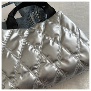 Détail du sac fourre-tout argenté matelassé avec texture bouffante et poignées noires