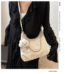 Detail of cream shoulder bag with ruched texture, silver chain and cute cloud charm