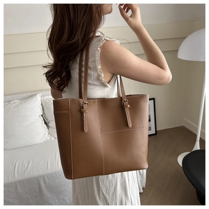 Sac fourre-tout en cuir marron avec surpiqûres blanches et bandoulière réglable sur modèle