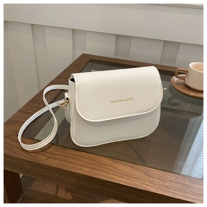 Detail view of the white saddle bag showing gold logo and smooth leather texture