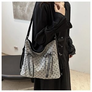 Detail of grey heart pattern tote with dual front zippers and decorative black bows