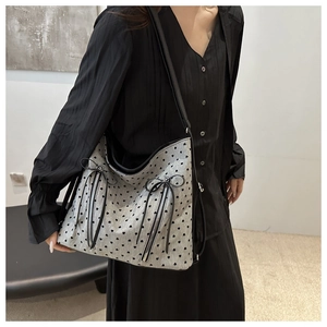 Detail of grey textured tote bag with black heart patterns and bow zipper accents