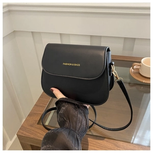 Detail showing hand holding black semi-circular saddle bag with golden lettering