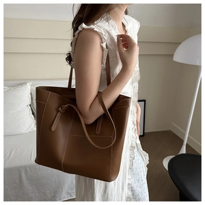 Détail d'un sac cabas en cuir marron foncé avec surpiqûres sur un mannequin femme