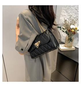 Detail of a black quilted leather shoulder bag with gold chain and heart metal lock