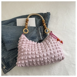 Détail du sac à main en seersucker rose avec poignée en perles de bois sur denim
