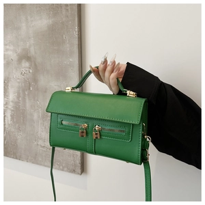 Détail du sac à main vert en cuir avec doubles fermetures éclair dorées et anse