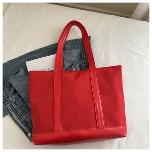 Detailed top view of large red canvas tote bag with leather trim on white bedding