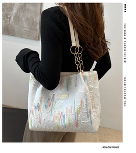 Détail du sac cabas blanc avec broderie vagues colorées et chaîne en métal doré