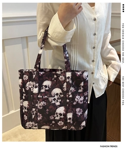 Detail of gothic skull and floral print tote bag with reinforced handles shown by a model