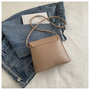 Minimalist khaki bucket bag shown with a blue denim jacket and art book in a lifestyle setting