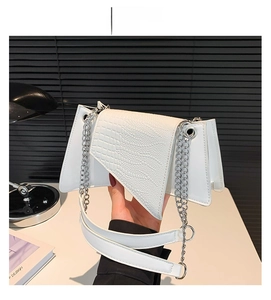 Détail du sac blanc effet crocodile avec plis en accordéon et bandoulière chaîne