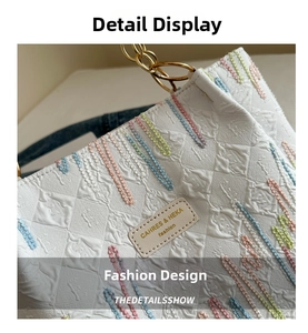 Détail macro du sac blanc texturé avec broderies colorées et bandoulière chaîne dorée