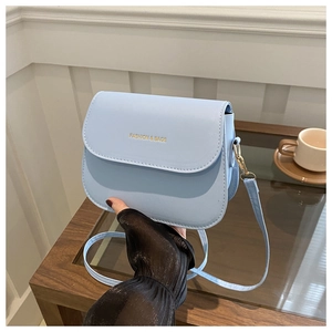 Detail of light blue crossbody bag with gold Fashion & Bags lettering and metal clasp
