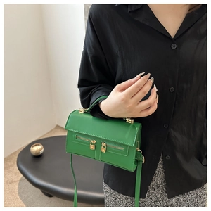 Détail du sac à main en cuir vert vif avec double fermeture éclair et cadenas dorés