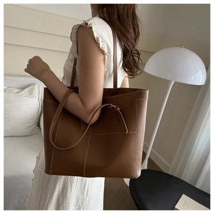 Vue détaillée d'un sac cabas en cuir marron avec surpiqûres contrastées et poche externe