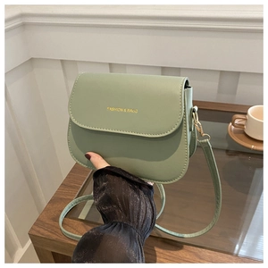 Detail of mint green minimalist saddle bag with golden lettering and leather strap