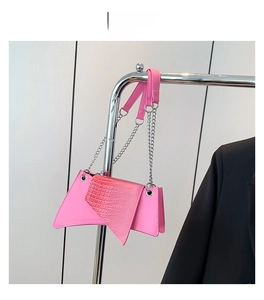 Sac rose asymétrique à motif crocodile avec bandoulière chaîne présenté sur un cintre