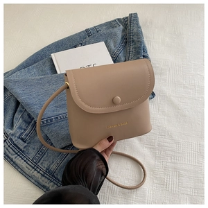 Close-up of light brown crossbody bag with matte texture and decorative snap closure