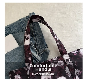 Detail of reinforced double-stitched handle on dark skull and floral printed tote bag