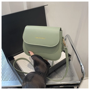 Close-up of mint green saddle bag with gold logo and fine stitching details