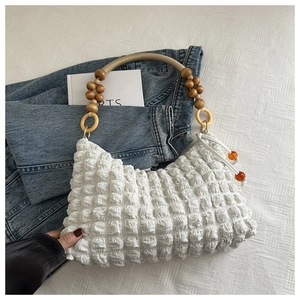 Détail du sac à bandoulière blanc froncé avec perles en bois et poignée en cuir