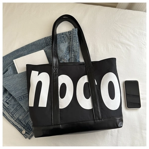 Close-up of canvas tote bag with noco print, leather handles and stylish lifestyle props