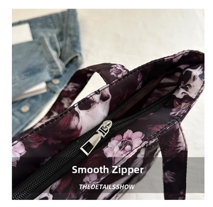 Close-up of smooth silver metal zipper and skull floral pattern on tote bag