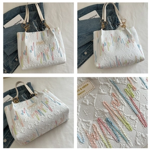 Détail du fourre-tout blanc avec broderie de chaîne macaron et quincaillerie dorée