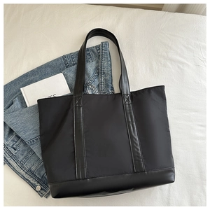 Detail of black large capacity canvas tote bag with leather handles and reinforced base