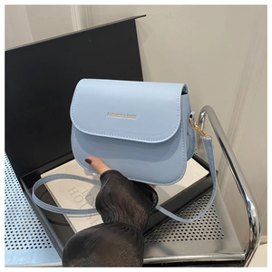 Detail of light blue matte leather saddle bag with gold 'FASHION & BAGS' lettering