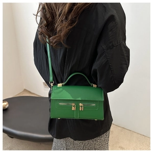 Détail du sac bandoulière vert avec doubles fermetures éclair et cadenas dorés décoratifs