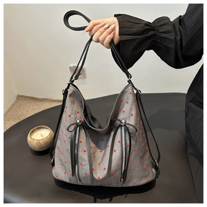 Close-up of a grey knit Boston bag with red polka dots and vertical metal zipper pockets